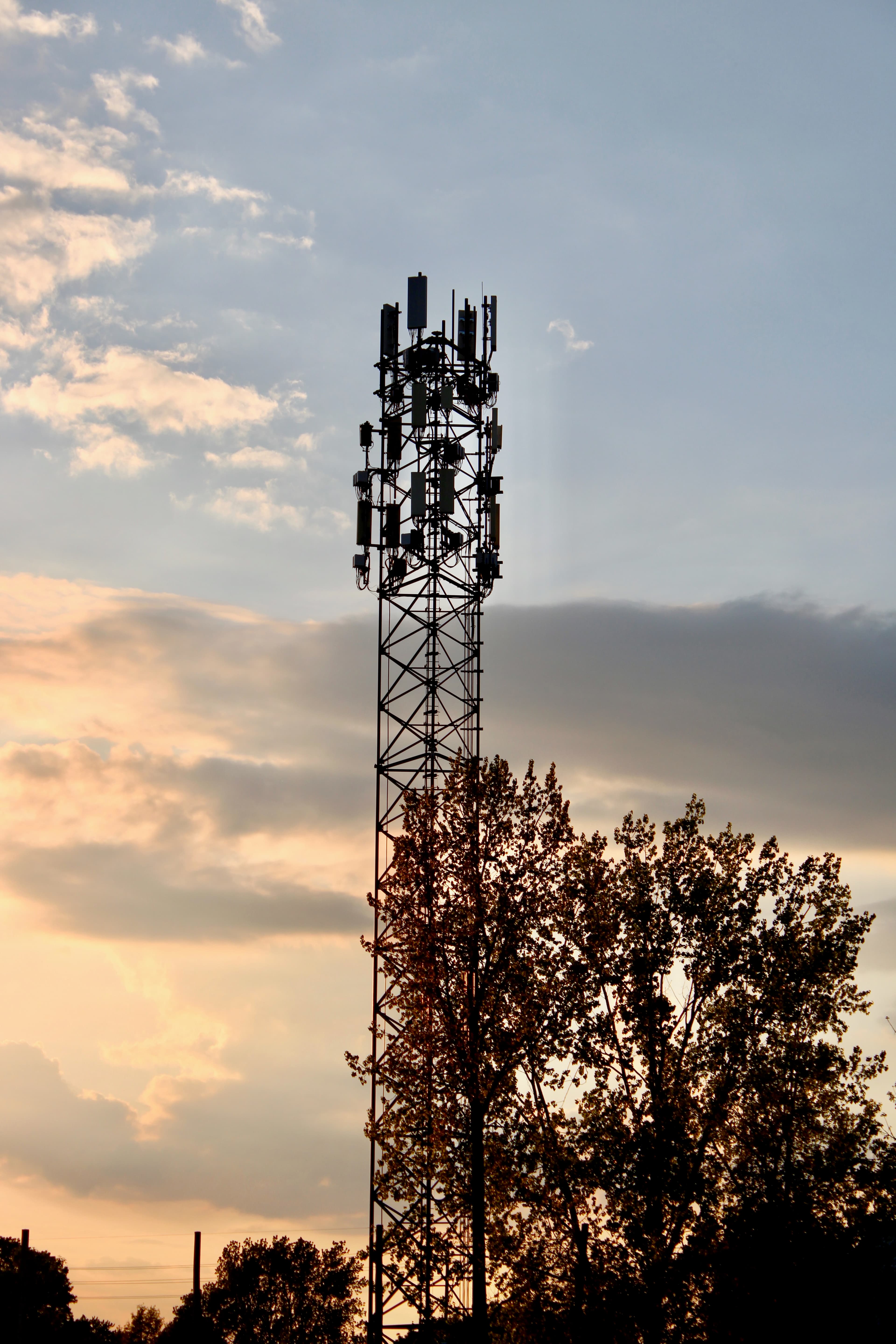 Cell phone tower silhouetted against dramatic sunset sky
