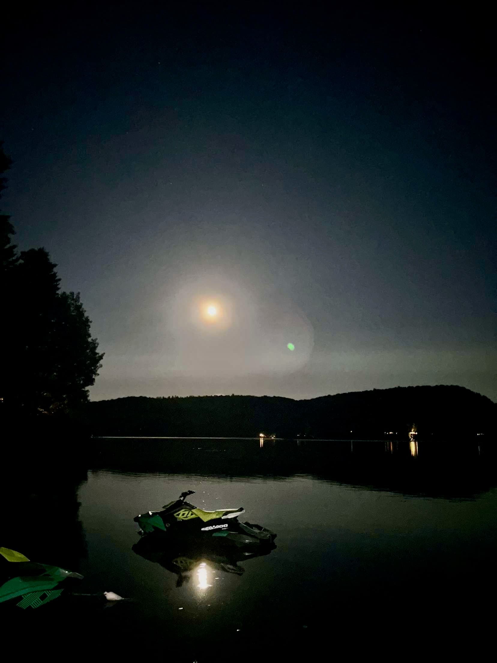Moonlit lake scene with jet ski and atmospheric sky